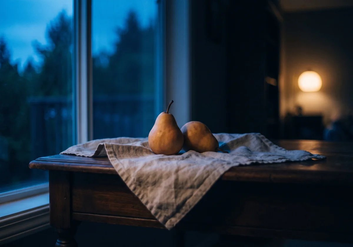 Two pears on a linen cloth by a window at dusk, the background falling softly out of focus